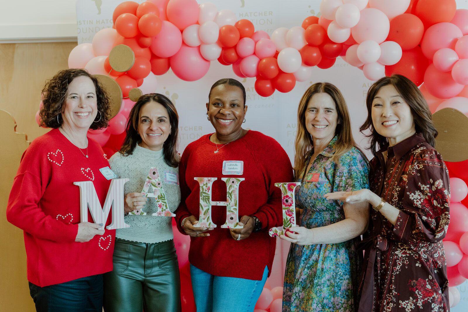 Mahj For A Cause community members holding MAHJ letters